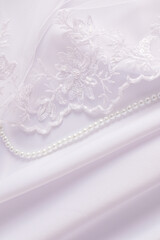 chic wedding background for design, card layout, invitation, cover, space for text. part of embroidered tulle, pearl beads on white satin with pleats.