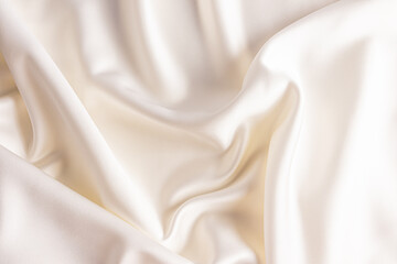 Elegant satin fabric with a beige color. The luxurious texture of the soft folds of the fabric. The concept of a festive wedding background. design