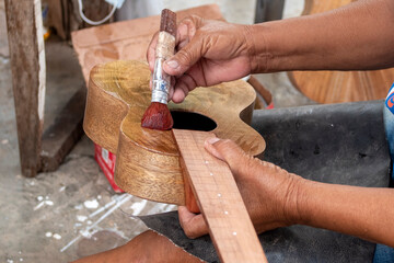 A ukulele being varnished by a craftsman