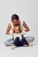 Mother and daughter bonding moment woman sitting on floor combing little girl's hair in a tender family beauty ritual