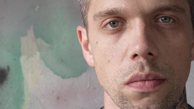The face of a serious, strict man with blue eyes. Close-up portrait. The man looks straight into the camera. Abstract background. Slow motion. High quality 4k footage