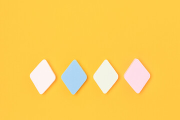 Multicolored makeup sponges neatly layed on a yellow background. Place for text.