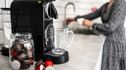 Coffee machine with capsules and transparent cup at domestic kitchen at home. Espresso caffeine beverage maker and modern mug