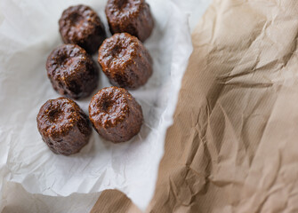 Caneles de bordeaux - traditional French sweet dessert with table background,Cannelés Recipe,small pastry rum and vanilla on a wooden plate,close up,french food,french cuisine,French Tourism,olympic