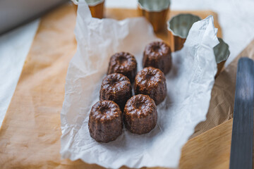 Caneles de bordeaux - traditional French sweet dessert with table background,Cannelés Recipe,small pastry rum and vanilla on a wooden plate,close up,french food,french cuisine,French Tourism,olympic