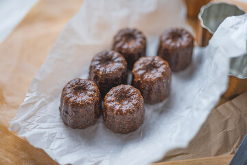 Caneles de bordeaux - traditional French sweet dessert with table background,Cannelés Recipe,small pastry rum and vanilla on a wooden plate,close up,french food,french cuisine,French Tourism,olympic