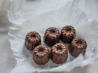 Caneles de bordeaux - traditional French sweet dessert with table background,Cannelés Recipe,small pastry rum and vanilla on a wooden plate,close up,french food,french cuisine,French Tourism,olympic