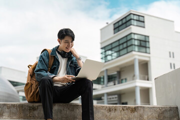 Fototapeta premium Young Traveler Using Laptop Outdoors in Urban Setting with Modern Architecture in the Background