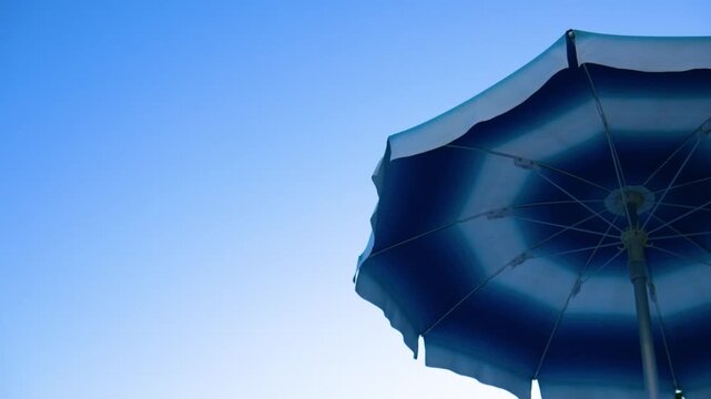 Beach umbrella in blue colors against a clear sky background with empty copy space