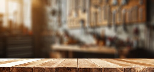 Empty wooden work table with space for tools and products. Blurred background of craft workshop and wall with tools.