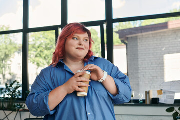 A plus size businesswoman with vibrant red hair enjoys a cup of coffee by a window.