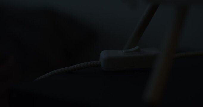 Close-up of female hand turning off light touching lamp switch on bedside table and sleeping at night. Time to sleep concept.