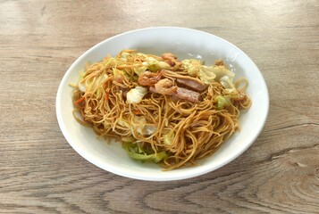 stir fried Hong Kong noodles cabbage and meat with slice bacon topping dry shrimp on plate