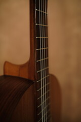 Fototapeta premium Close up, cinematic, classical guitar at studio textured background. Guitar neck,playing chord, 