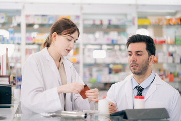 Fototapeta premium Two pharmacists counting drug pills arranging assortment working in drug shelves counter