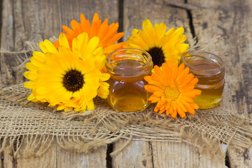 honey and calendula flowers on wooden background