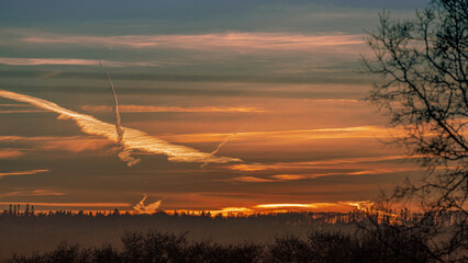 Sunrise sky showing plane contrails firing into the sky, space for text
