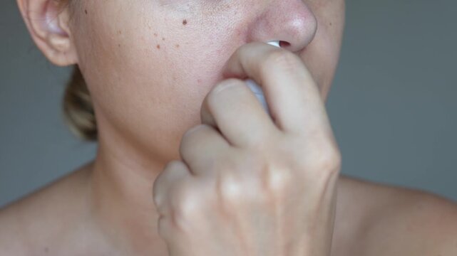Young caucasian woman using nasal spray for stuffy nose and congestion on dark gray background. Treatment of the disease. Rhinitis, sinusitis, seasonal allergy, runny nose, relief of nasal congestion