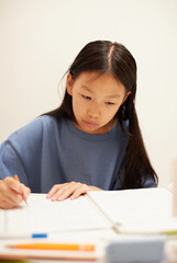 夏休みの小学生の女の子が家で宿題をする姿