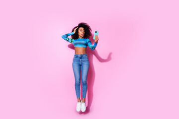 Full size photo of lovely young lady hold device jumping amazed dressed stylish blue garment isolated on pink color background