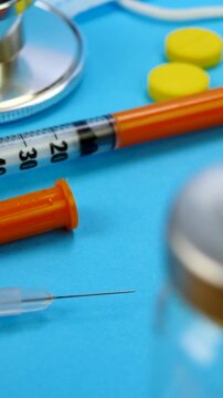 Heap of pills, syringe for insection, stethoscope and vaccine vial on blue background. Health care, doctor, clinic or hospital concept. Medical equipment