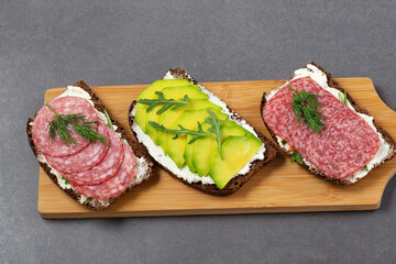 Healthy sandwiches with cottage cheese, arugula, avocado, sausage, ham
