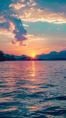 Fototapeta premium Sunset reflecting on calm water with mountains in the distance