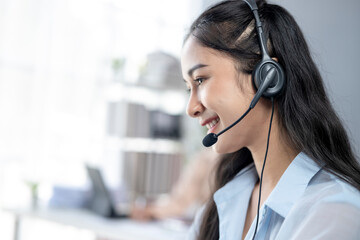 A woman wearing a headset is smiling while talking on the phone