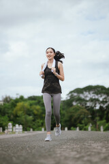A young woman jogs in the city on a summer morning, embodying an active lifestyle. This fit athlete, dressed in sports clothing, enjoys outdoor exercise, promoting health, vitality, and a healthy life
