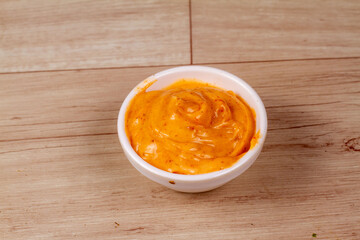 White Bowl of tasty chipotle sauce on wooden background