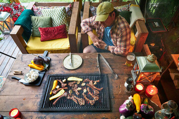 man in the summer kitchen grilling meat