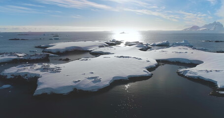 Aerial winter Antarctica snow covered coastline. Drone fly over cold polar ocean bay, low angle view. Untouched wilderness of Arctic nature, mountain in background. Explore travel to South Pole