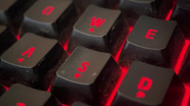 Close-up macro footage of a glowing RGB keyboard. The shot captures the intricate details of the backlit keys, showcasing a vivid array of colors and dynamic lighting effects
