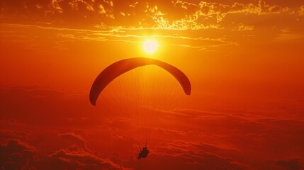 Paraglider in sunset sky, sun shines, awe-inspiring scene. Small silhouette against vast backdrop of orange and pink sky with clouds. No ground visible.