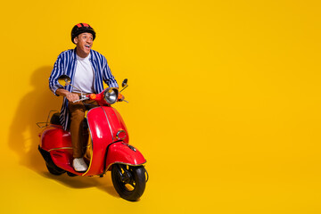 Full size photo of ecstatic man dressed striped shirt in helmet driving motorcycle look empty space isolated on vivid color background