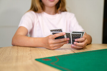 A girl is playing a card game with three cards in her hand