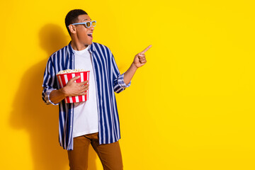 Photo of impressed man dressed striped shirt in 3d glasses eat popcorn directing look empty space isolated on vivid color background