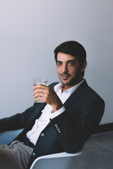 Concept of technology and communication, portrait of positive smiling manager looking at camera and holding glass with water sitting at desktop with laptop device waiting video conference with boss