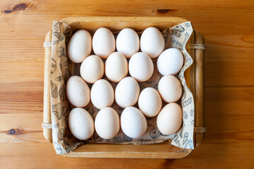 Rustic basket of fresh white eggs on wooden table, natural food concept, free-range chicken eggs