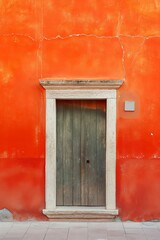 Fototapeta premium An aged orange wall with an old wooden door and cracked paint details, reflecting a vintage feel and charm.