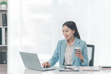 Happy Asian businesswoman working with laptop, analyzing business documents with financial graphs, market reports on digital tablet. accounting concepts