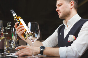 Sommelier looks at bottle of expensive wine in bar.