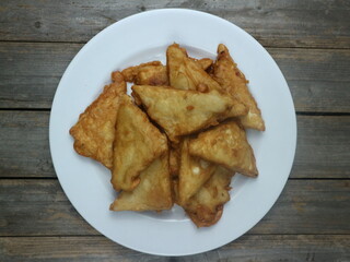 Crispy fried tempeh on a white plate with a gray plank background. Top Angle.