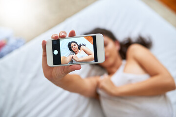 Phone screen, selfie and woman in bedroom in home for relaxing, calm and resting in morning on weekend. Comfy, tech and female person with photography app for picture on smartphone on bed at house.