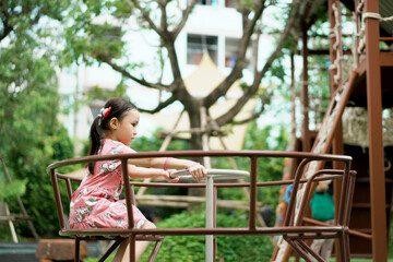 Naklejka premium Adorable little kid in summer time at park having a ride on the merry-go-round.
