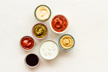 Set of sauces in bowls - pesto salsa mustard and others. Food background