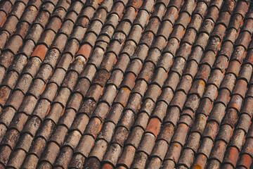 weathered tiles of old roof. Closeup of weathered rusty red tiles on roof of medieval building for textured background. 