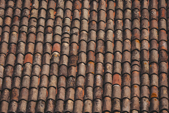 weathered tiles of old roof. Closeup of weathered rusty red tiles on roof of medieval building for textured background. 