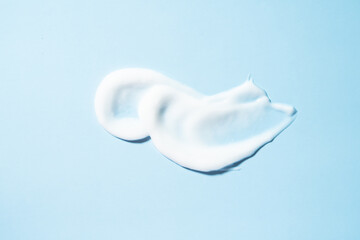 Cosmetic smears of creamy texture on a blue background. Flat lay.