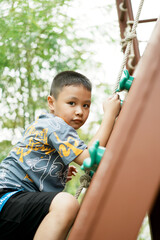 Adorable little boy having fun and climbing on wall at playground. Copy space.